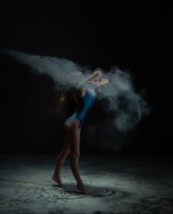 Graceful woman dancing in dust cloud profile view