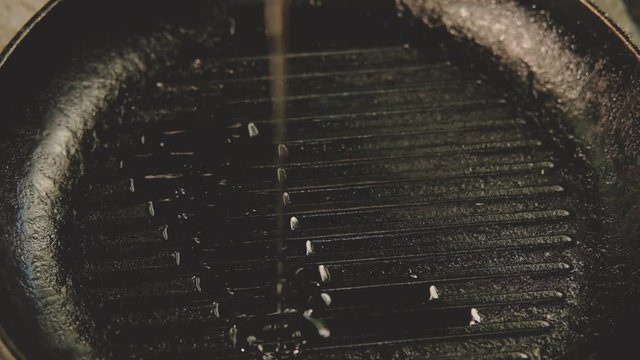 Cooking oil poured on hot frying pan. Professional grilled kitchenware