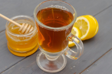 Composition of a cup of tea, sliced lemon and a jar of honey.