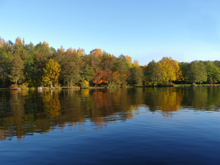 Fototapeta na wymiar Beautiful autumn landscape of colorful trees reflected in the blue water lake