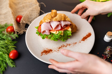 Breakfast croissant sandwich with ham and cheese. Top view. black background with vegetables. Slow-mo.
