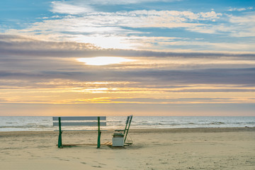  Very beautiful sunset on the sea and a place to relax on the shore near the water. Two benches on the sandy seashore.