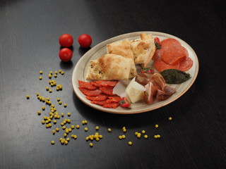 Snack on a plate with cheese, salami, bacon and pita bread