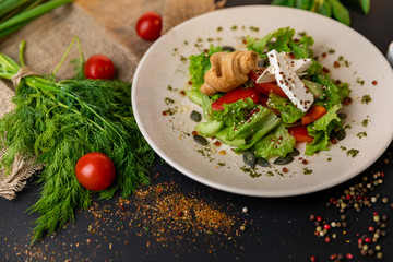 Greek salad of fresh cucumber, tomato, sweet pepper, lettuce, red onion, feta cheese and olives with olive oil. Healthy food, top view. Black background . Slow-mo.