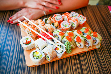 assorted sushi on the table at the girl. Japanese food rolls in the restaurant. Girl's Order Traditional Japanese Food.