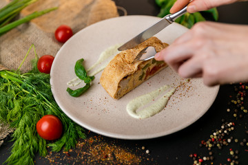 Large portion of healthy colorful vegetable lasagne made with assorted fresh veggies layered with melted mozzarella and pasta served on a white plate. Black background . Slow-mo