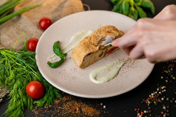 Large portion of healthy colorful vegetable lasagne made with assorted fresh veggies layered with melted mozzarella and pasta served on a white plate. Black background . Slow-mo