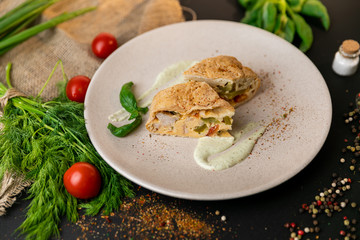 Large portion of healthy colorful vegetable lasagne made with assorted fresh veggies layered with melted mozzarella and pasta served on a white plate. Black background . Slow-mo