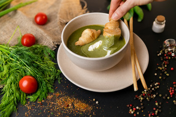 Green cream soup of spinach and broccoli. with the addition of parmesan and blue cheese with croissant. a black background. conception healthy food and diet. Slow-mo.