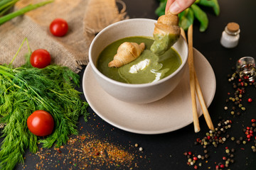 Green cream soup of spinach and broccoli. with the addition of parmesan and blue cheese with croissant. a black background. conception healthy food and diet. Slow-mo.
