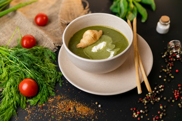 Green cream soup of spinach and broccoli. with the addition of parmesan and blue cheese with croissant. a black background. conception healthy food and diet. Slow-mo.