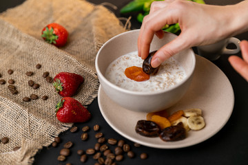 Tasty breakfast. Top view of a bowl of muesli with oats, nuts and dried fruit on black table. Slow-mo.