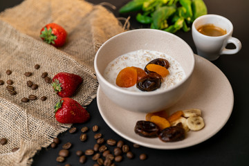 Tasty breakfast. Top view of a bowl of muesli with oats, nuts and dried fruit on black table. Slow-mo.