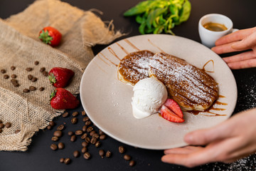 Tasty breakfast. Closeup of pancakes with fresh fruits, ice cream and whipped cream. Black background. Slow-mo.