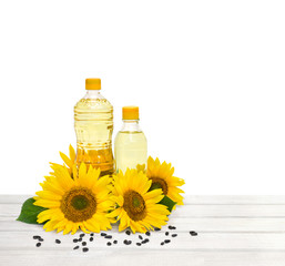 Bottles of sunflower oil with flowers and seed of sunflower on wooden white table on a white background with space for text