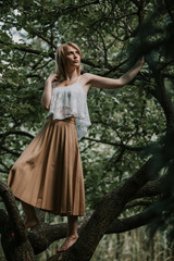 Obraz na płótnie Canvas Pretty blonde stands barefoot on tree branch