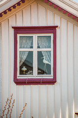 Lamp and a figure of a bird in a window of a white house.