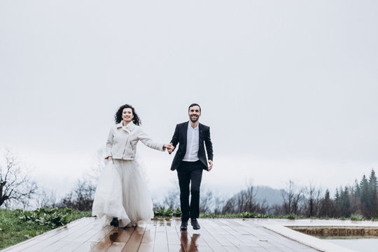Stylish couple of brides in a wedding walk during a cloudy weather in the mountains. Fog and mist, but the brides are happy and smiling at the wedding photo shoot