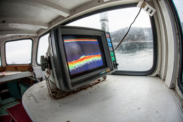 A sonar mounted in a wooden fishing boat, showing the sea bed.