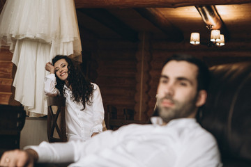 selective focus bride, husband and wife in the morning before the wedding in a large wooden house dressed in white shirts