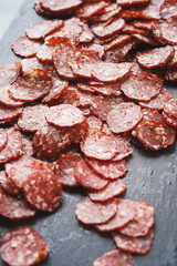 Thinly sliced sausage slices on a black stone board. 