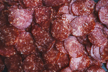 Thinly sliced sausage slices on a black stone board. 