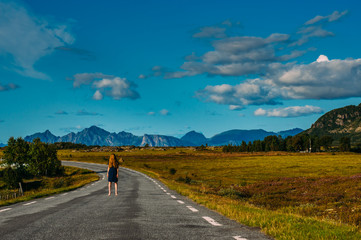 Girl in blue dress staying on the road  in  Straumnes