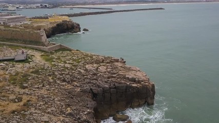 Aerial footage of a beautiful view of the  Rocky coast, port and the fort from above in Peniche, Portugal. 4k quality in motion.