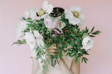Portrait of young girl with peonies flowers on pink background. Summer floral composition. space for text