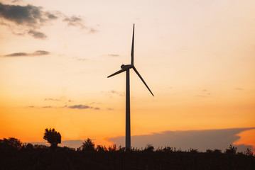 Obraz premium Turbina wiatrowa wytwarzająca zieloną energię podczas zachodu słońca