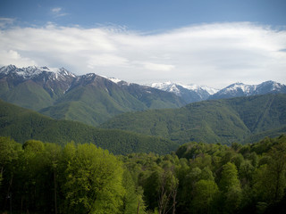 Fototapeta premium Beautiful green mountains below and mountains with snow at the height of Krasnaya Polyana