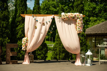 Wedding arch decoration with flowers on summer sunny day