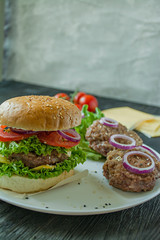 Fresh homemade burger on a white plate. Ingredients for cooking burger. Unhealthy food.