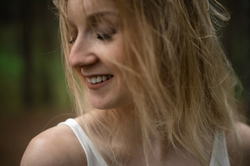 Close up portrait - Beautiful young blonde woman forest nymph in white dress in evergreen wood