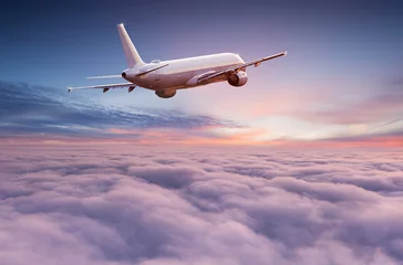 Poster Commercial airplane jetliner flying above dramatic clouds in beautiful sunset light. Travel concept. © Lukas Gojda