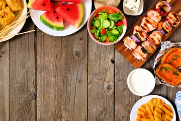 Summer BBQ or picnic food corner border. Selection of grilled meat, fruits, salad and potatoes. Top...