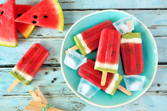 Homemade watermelon popsicles on a plate. Top view on a rustic blue wood background. Summer food concept.