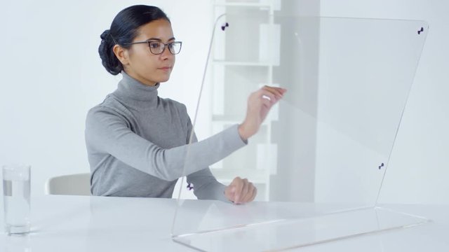 Lockdown of female Asian office worker sitting at desktop and swiping on invisible futuristic computer. Suitable for adding AR graphics