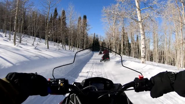 POV clip of a man riding motor sledge and following two snowmobiles on road. This clip shows point of view shot as man drives the snowmobile and traces other motor sledges. 
