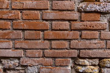 A crumbling old wall in Venice. Showing exposed bricks and neglected plaster work. Most of the brickwork is orange in colour