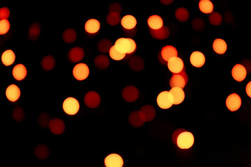 Abstract bokeh texture on black background. Defocused sparkles. Warm tone.