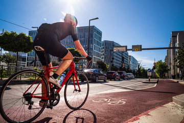 Cyclist ride along a red lane marked with a bicycle symbol, through a business area in Oslo, Norway. - obrazy, fototapety, plakaty