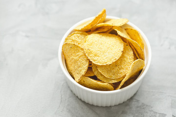 Tortilla corn chips in bowl on a gray background