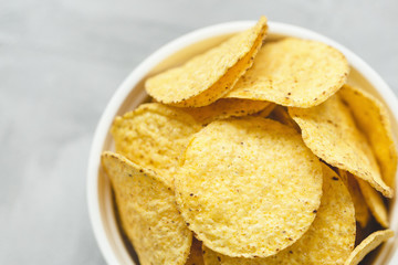 Tortilla corn chips in bowl on a gray background