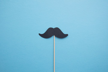 Black paper mustache on a blue background. Father's day or mens health concept