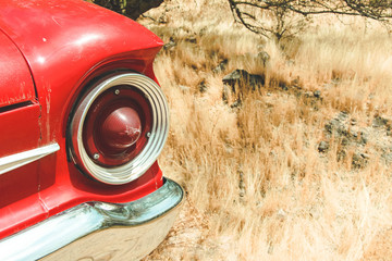 Close up on a tail light on a red car in the desert