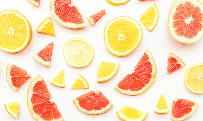 Fresh summer citrus grapefruit, orange and lemon slices pattern on white background flat lay top view