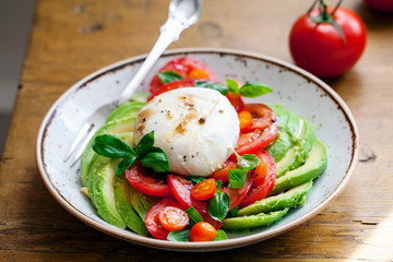Mozzarella, tomatoes and avocado with basil and olive