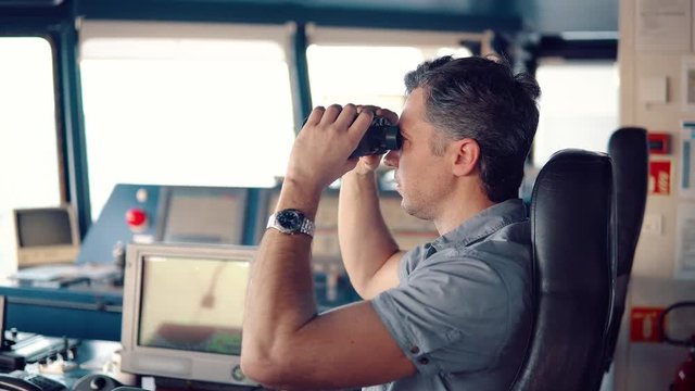 Navigational officer lookout on navigation watch looking through binoculars. Marine industry. COLREG collision regulations