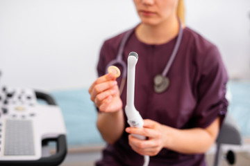 Ultrasound special sensor of modern ultrasonic scanner for intavaginal checkup and small medical condom for it in young woman doctor's hands preparing for a device scan. Helthcare concept